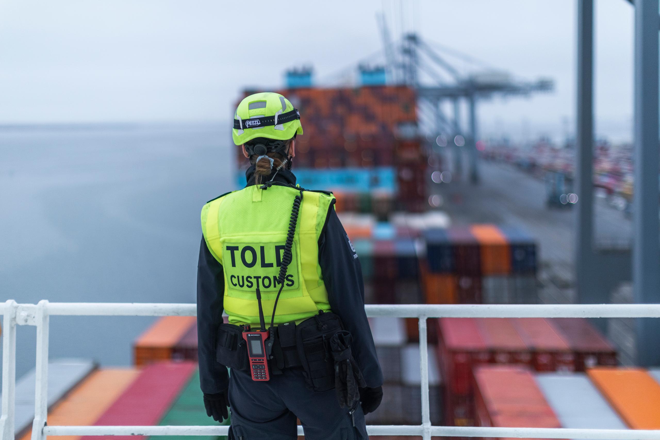 Tolder som kigger ud over containere på en havn